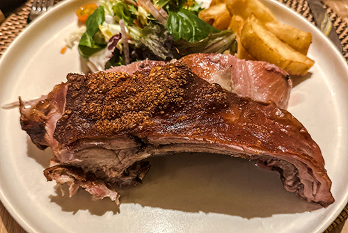 Ente mit Gewürzkruste liegt auf dem Teller wie ein Statement – dazu Kartoffeln und Salat, die ganz bescheiden wirken.
