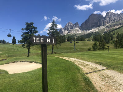 Golfplatz mit Bergkulisse und Seilbahn