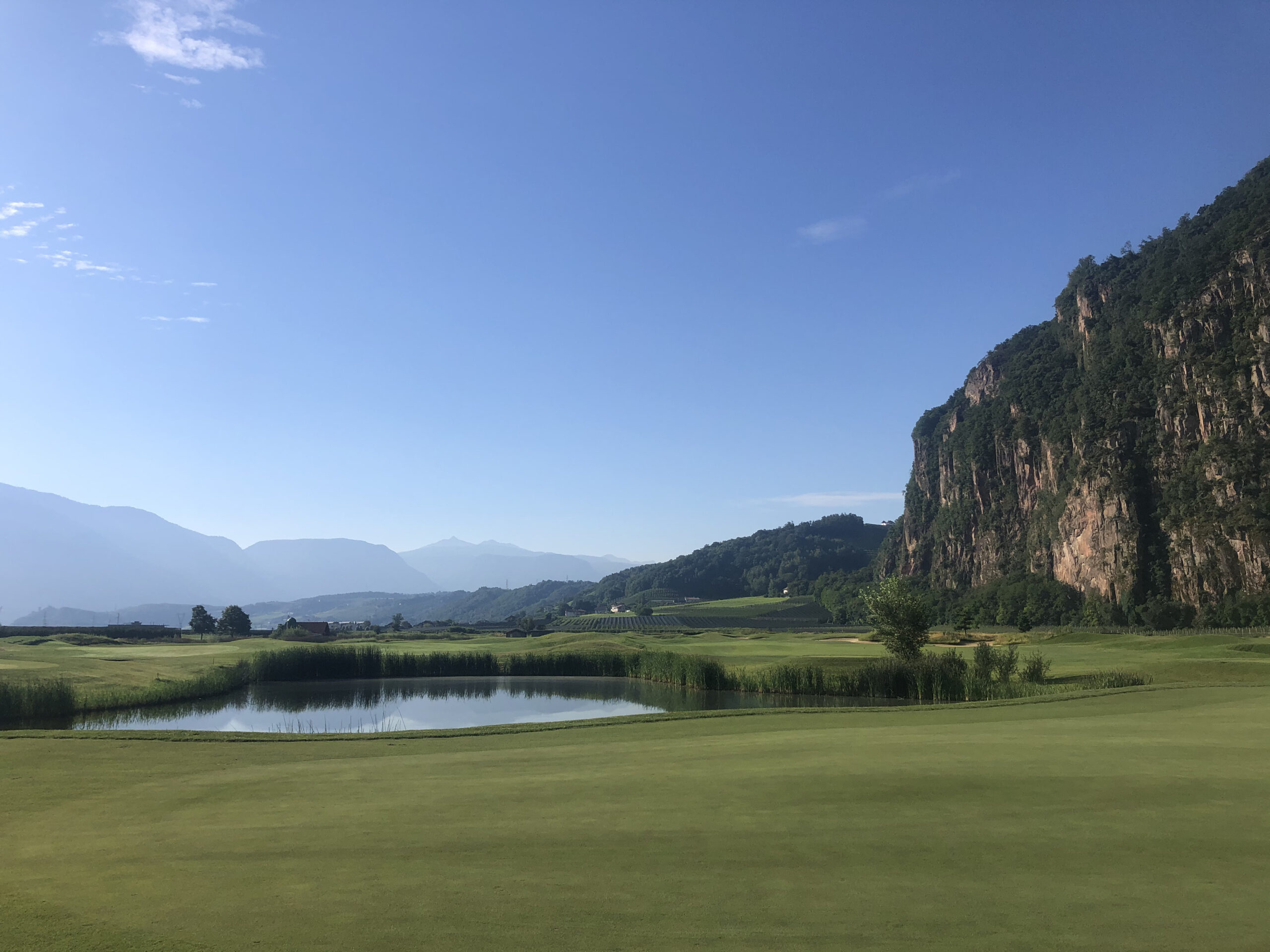 Grünes Golfplatz mit Berglandschaft