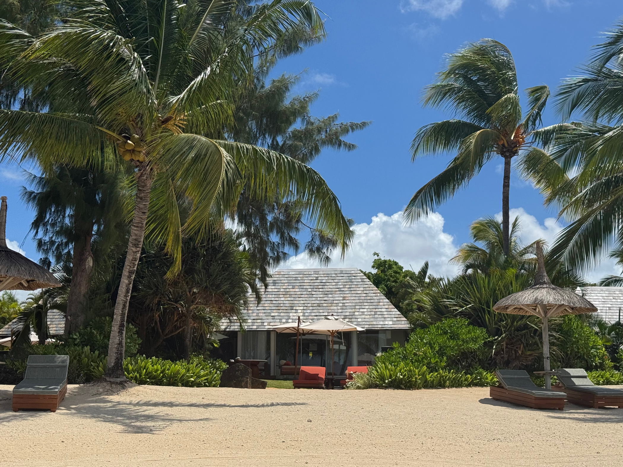 Tropischer Strand mit Palmen und Villa.