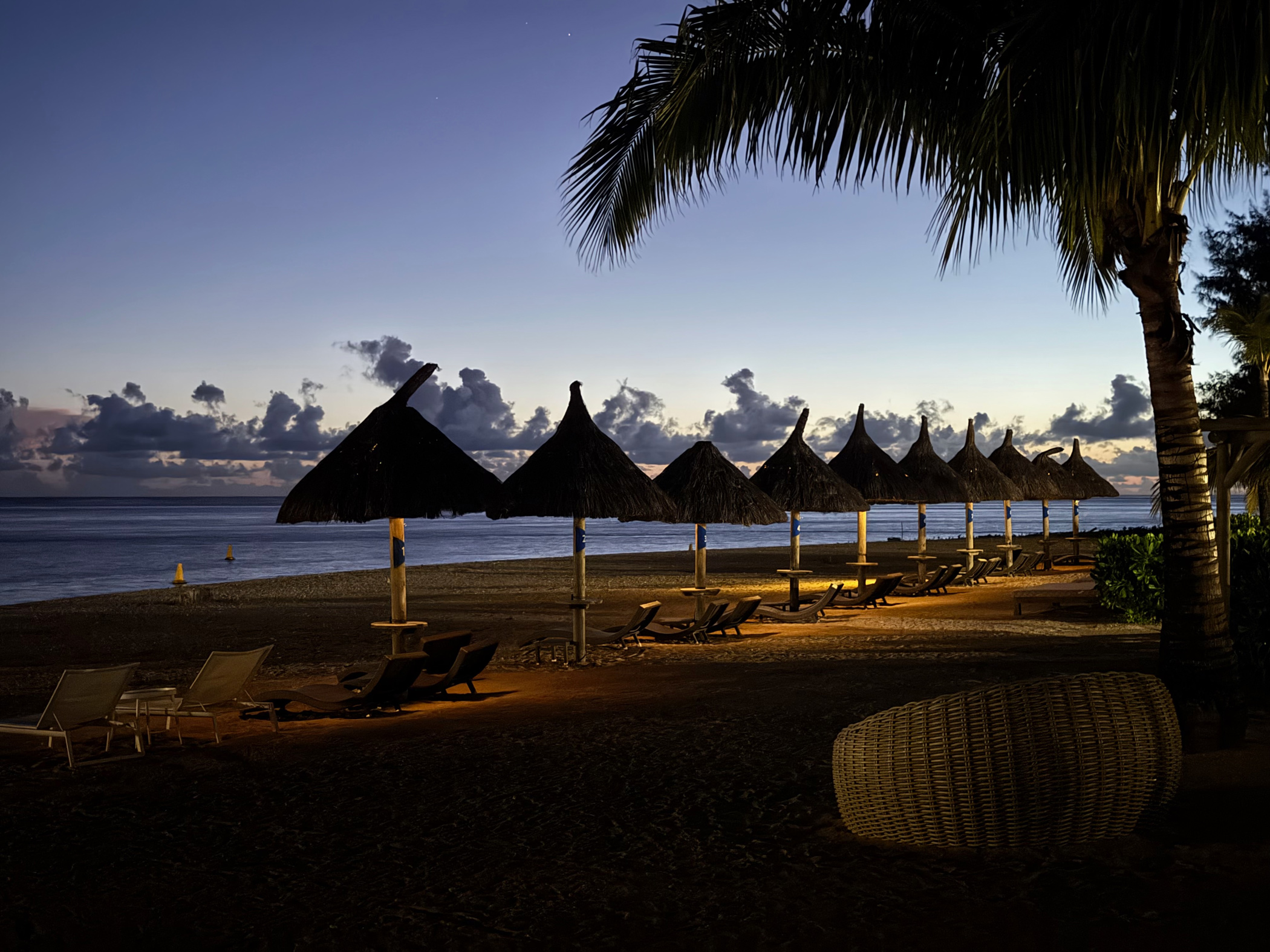 Strand am Abend im Heritage Le Telfair Mauritius mit beleuchteten Sonnenschirmen