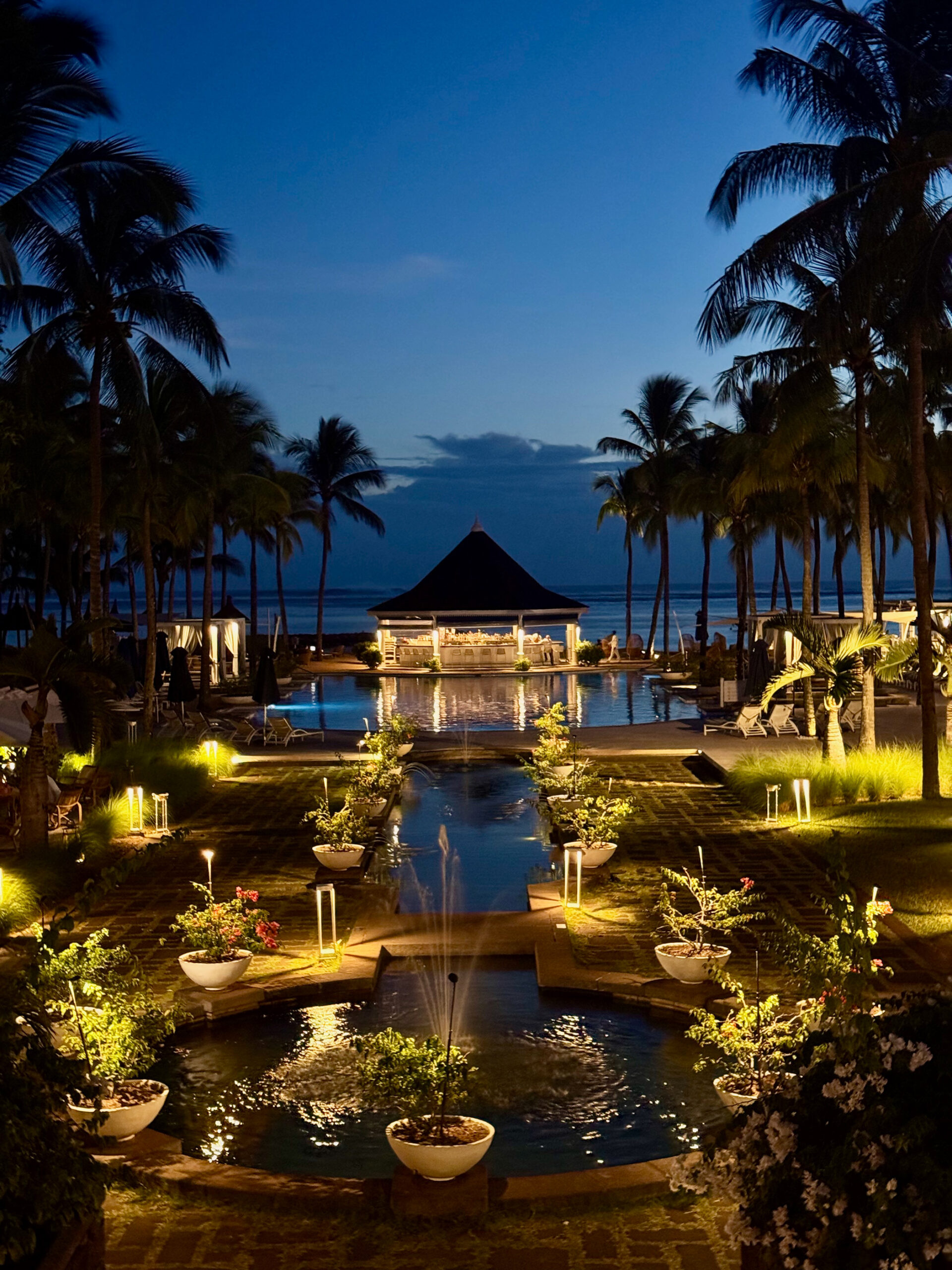Poollandschaft im Heritage Le Telfair Mauritius bei Nacht mit Palmen und Lichtern