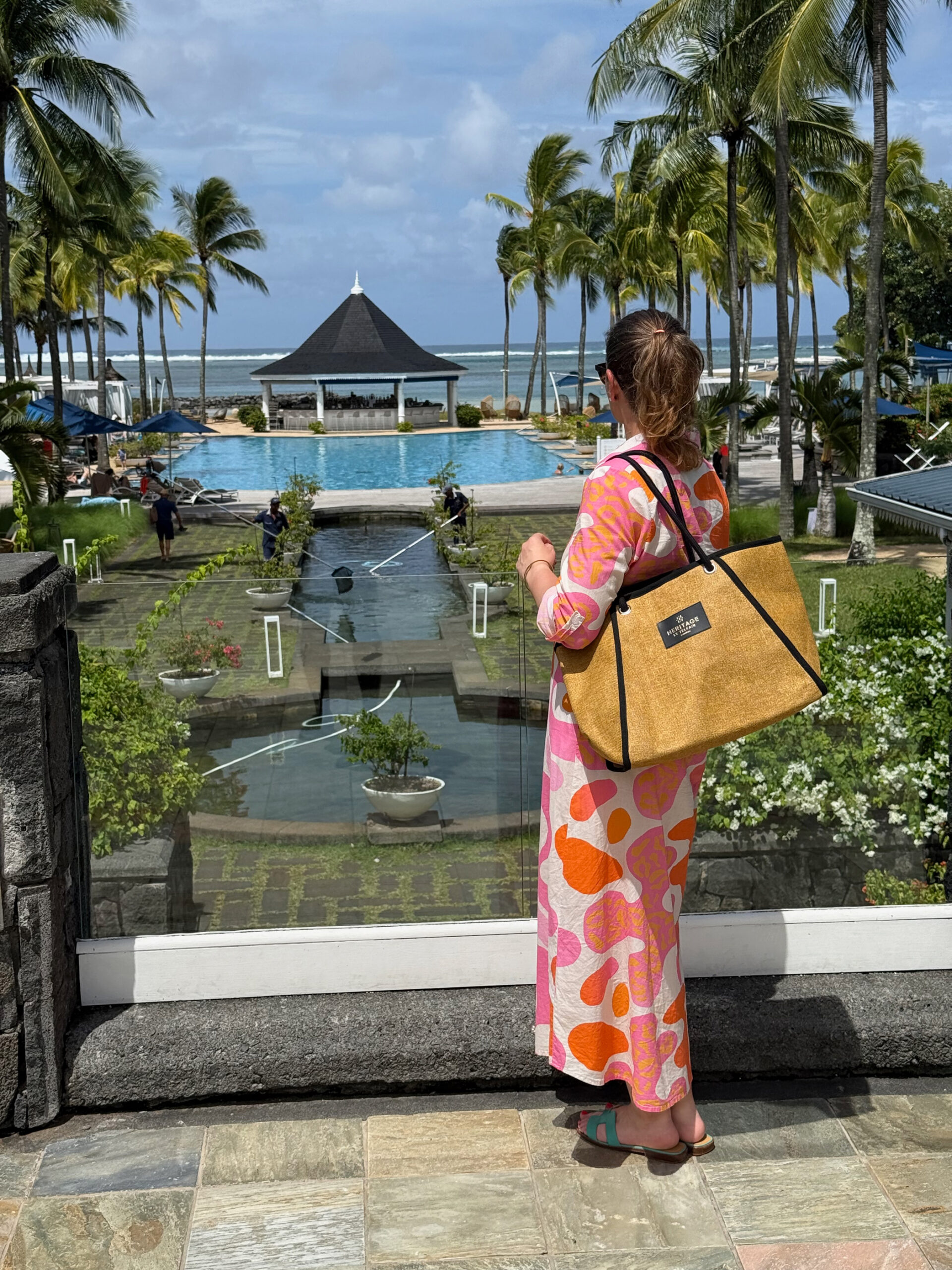 Frau mit Blick auf Garten, Pool und Strandpavillon