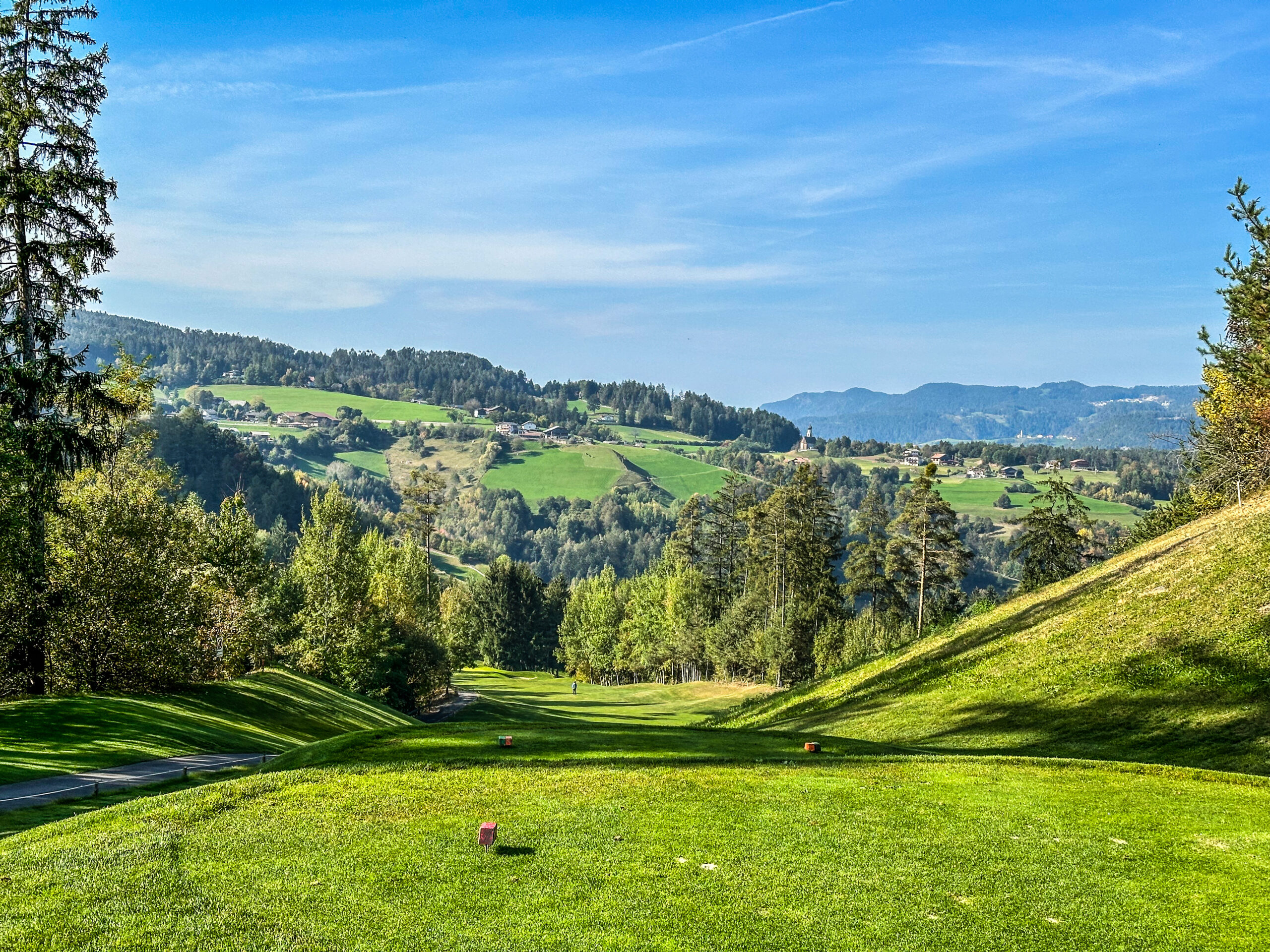 Grüner Golfplatz mit Bergblick.