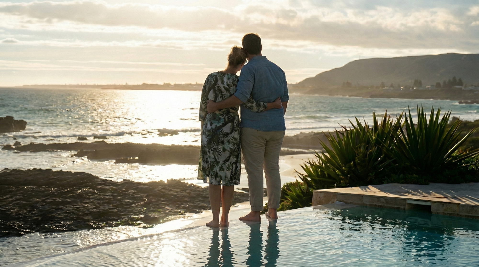 Liebespaar am Pool mit Aussicht auf das Meer im Sonnenuntergang in Südafrika im Birkenhead House