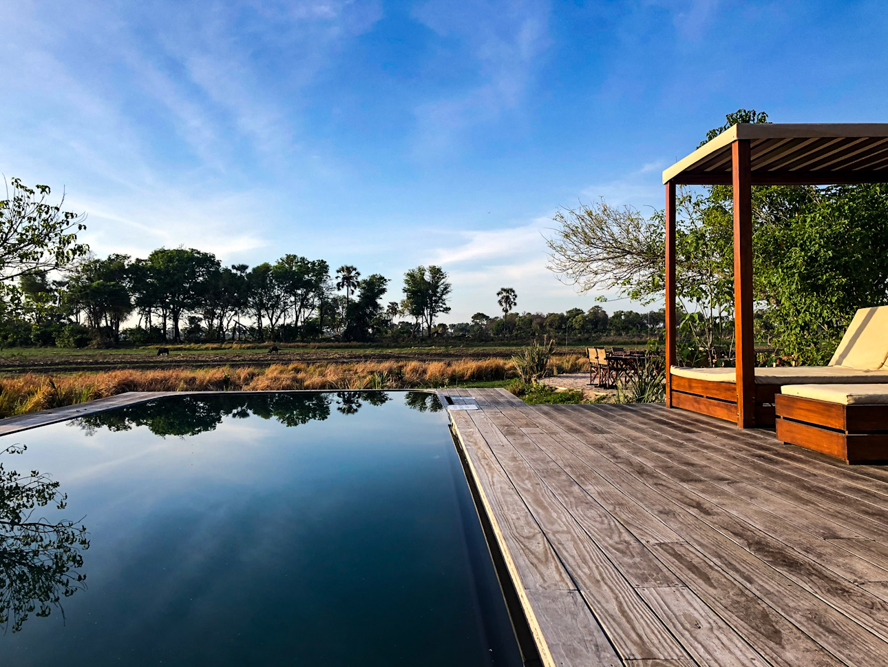 Spiegelglatte Wasserfläche vor Holzsteg und Holzpergola – die Wildnis fängt dort an, wo die Architektur aufhört.