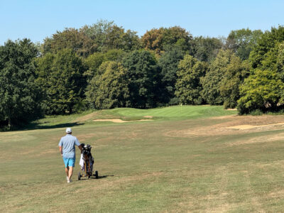Golfer geht mit Tasche über Fairway