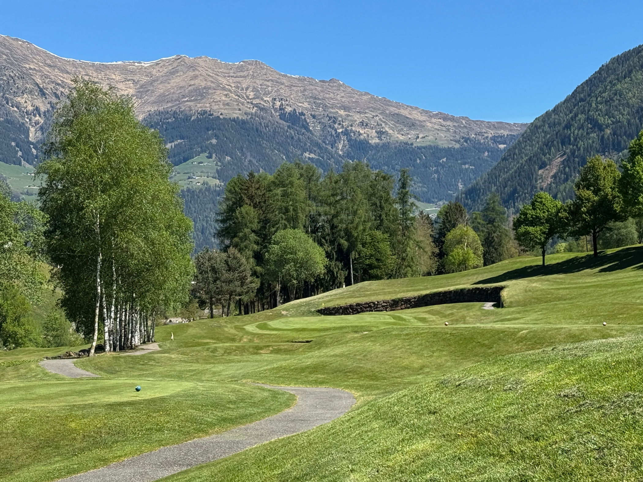 Grüner Golfplatz mit Bergblick.