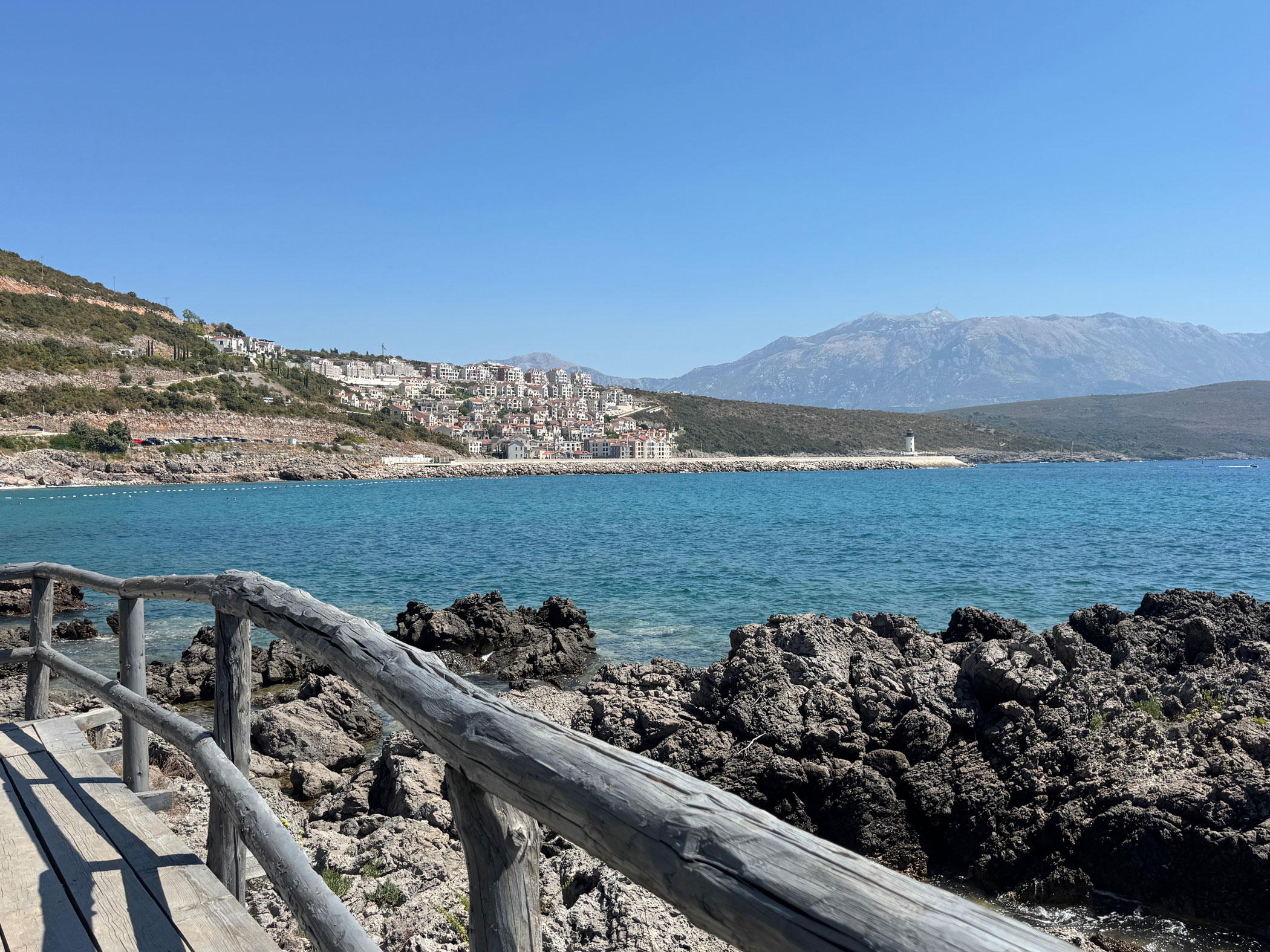Holzweg an der Küste in Luštica Bay mit Blick auf das türkisblaue Meer