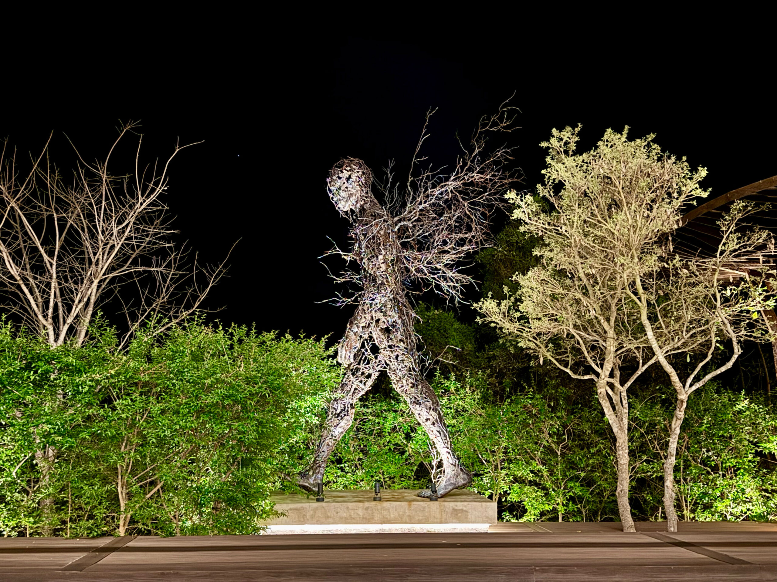 Skulptur «Twigs» Ein Mensch im weiten Ausfallschritt, mitten in der Bewegung nach vorn. Kopf und Körper sind ein dichtes Geflecht aus dunklen, verdrehten Metallstreben, durch das man stellenweise hindurchsehen kann.